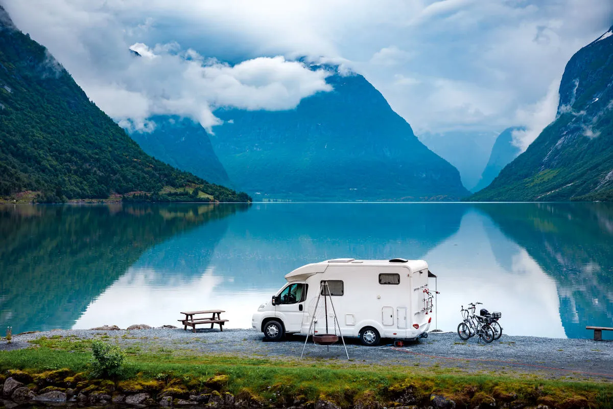 An RV boondocking at a dispersed campsite beside a mountain lake, camping self-contained with no hookups
