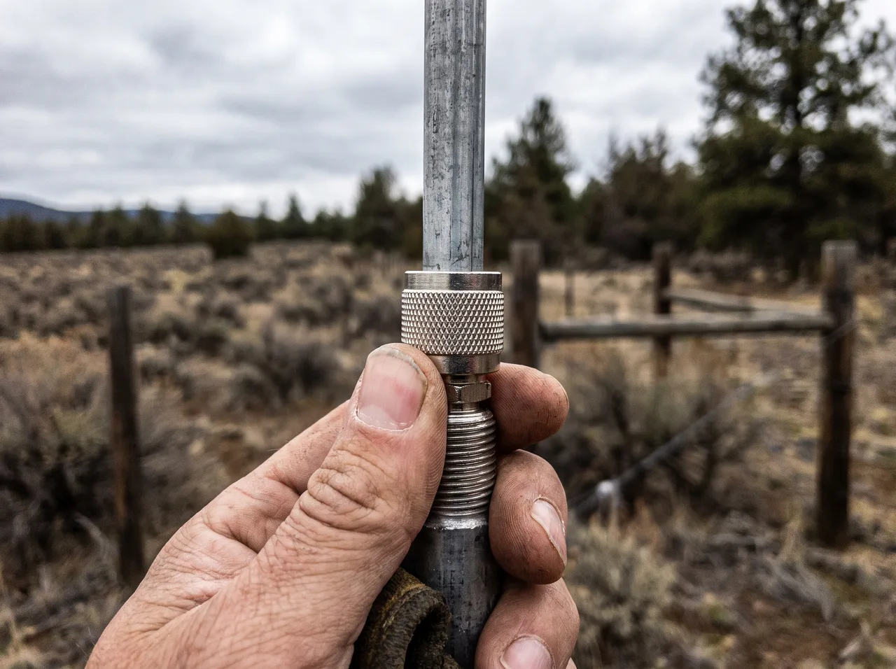 A coax connector being threaded onto an antenna base by hand, the knurled ring in close focus.